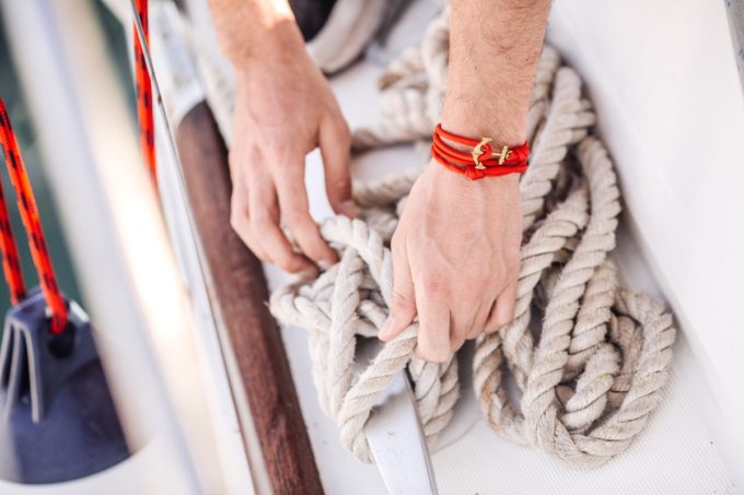 hands tie a rope on the yacht